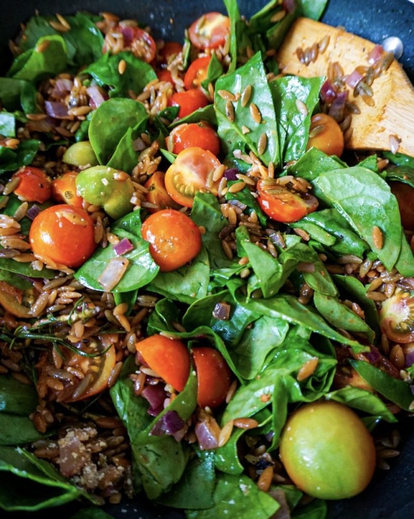 spinach and cherry tomatoes in skillet about to turn into a family weekday meal