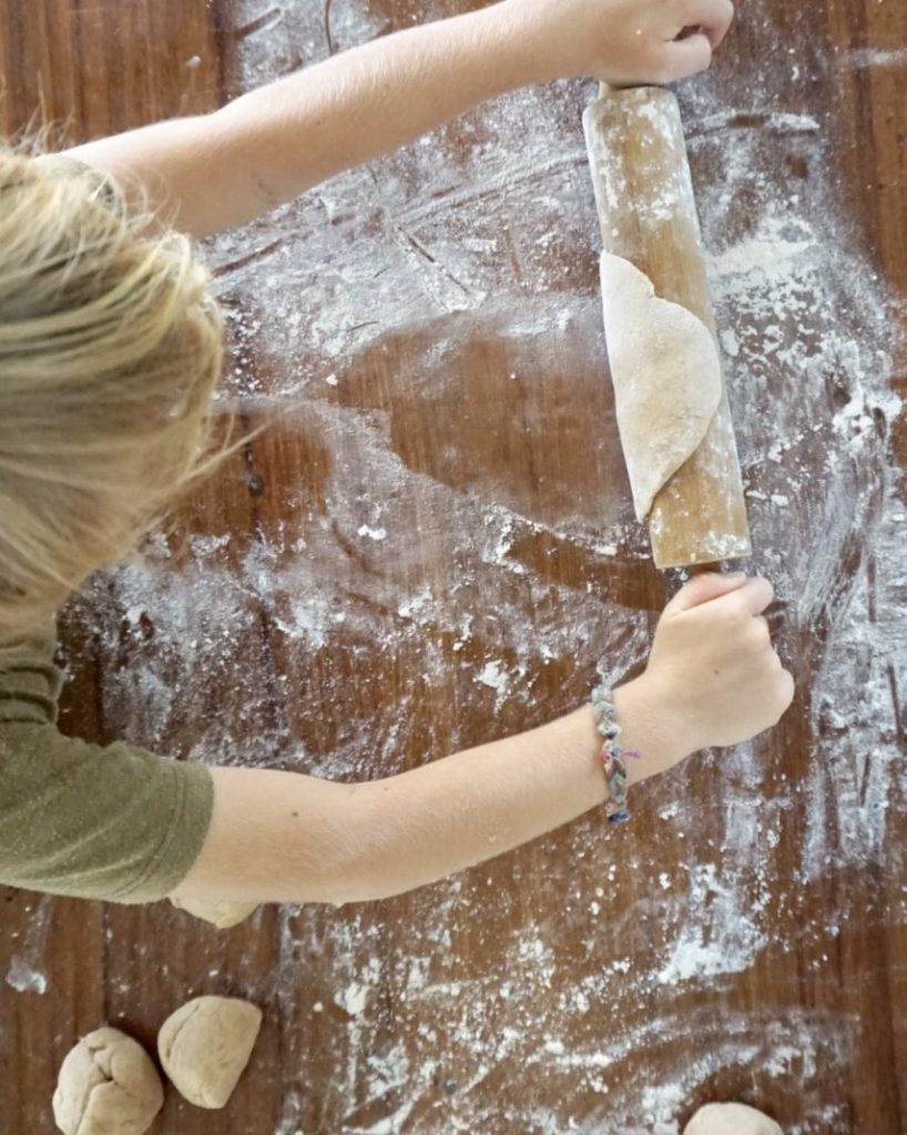 kid rolling out pizza dough