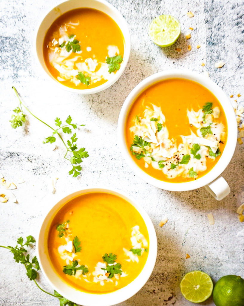 3 bowls of butternut squash soup with limes on the side