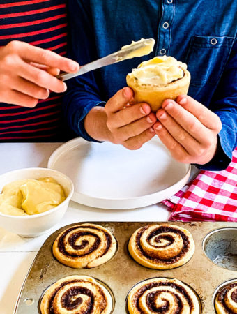 Kids spreading frosting on their cinnamon roll