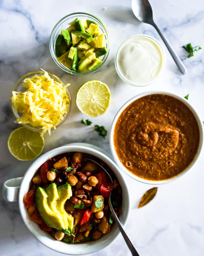 2 bowls of chili with garnishings on the side