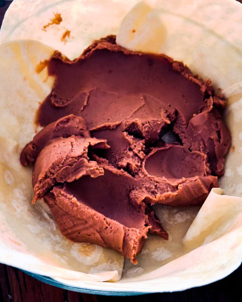 Spreading out refried beans on the bottom of the pie