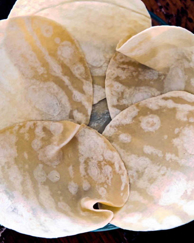Spreading out tortillas in a greased pie pan