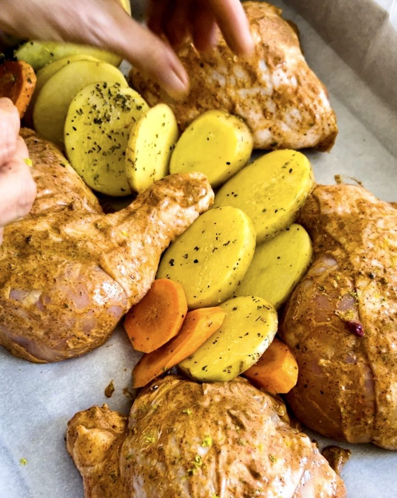 arranging chicken, potatoes and carrots on the baking tray