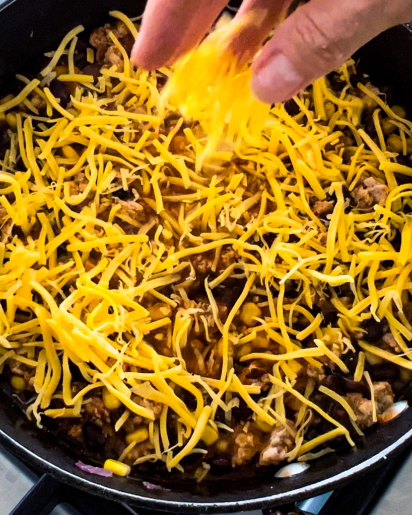 Quick And Easy Chicken Enchilada Dip A Recipe By Familicious   Adding Cheese To The Skillet E1682371497365 818x1024 