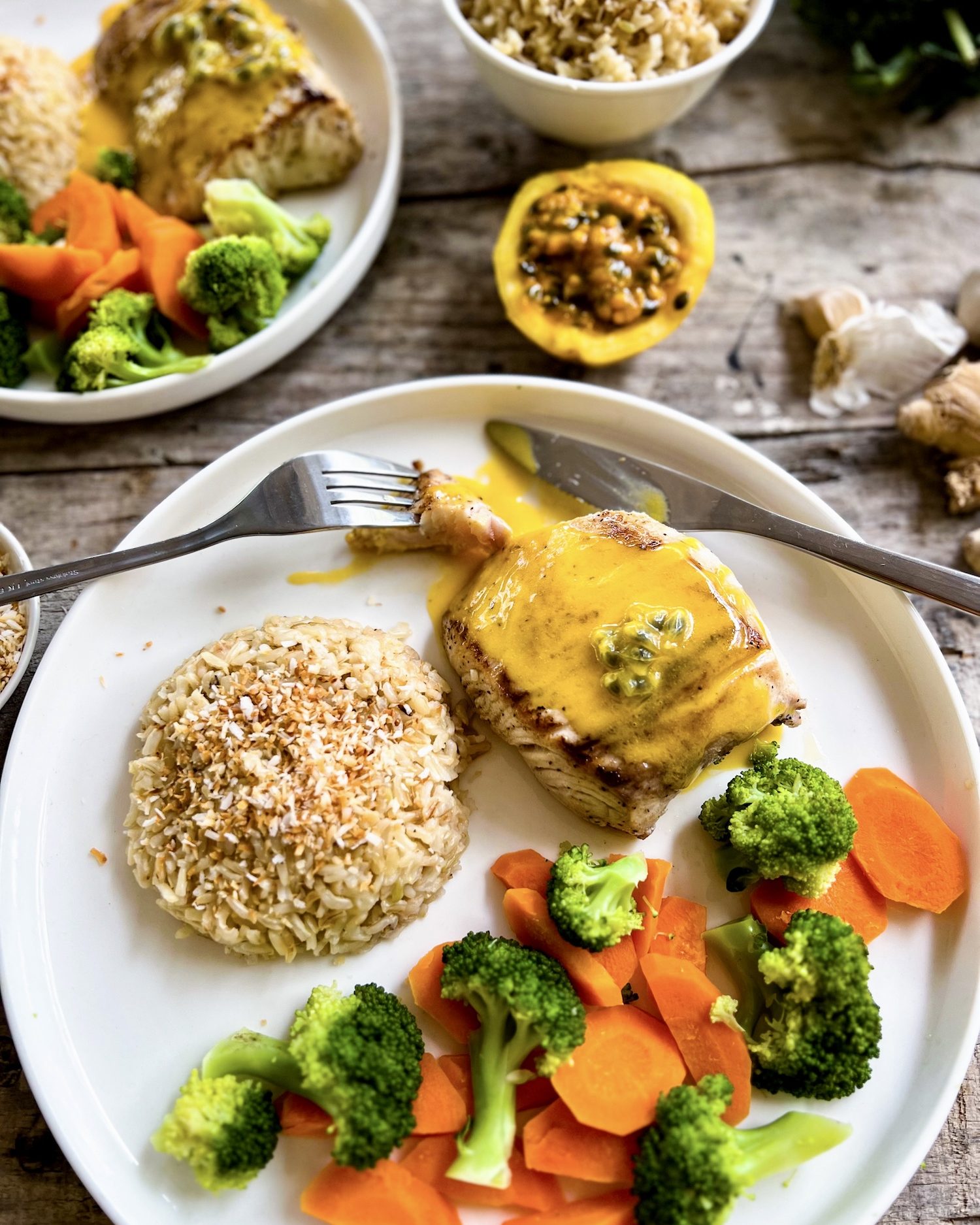 a close up of a plate of fish with passionfruit sauce, veggies and rice