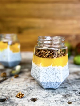 coconut chia pudding in a jar with mango puree and topped with homemade granola