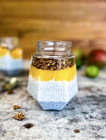 coconut chia pudding in a jar with mango puree and topped with homemade granola